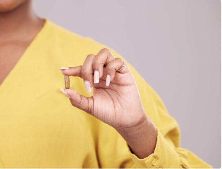 Hand holding a single supplement capsule