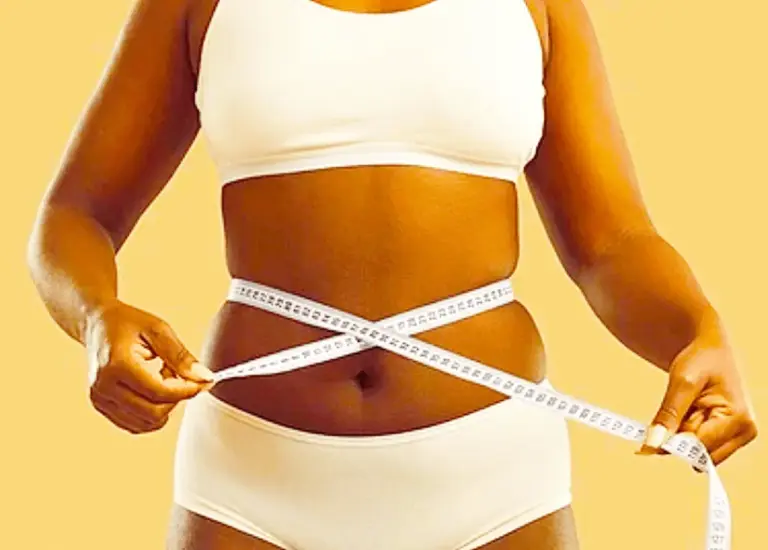 Woman measuring her waist with a tape measure